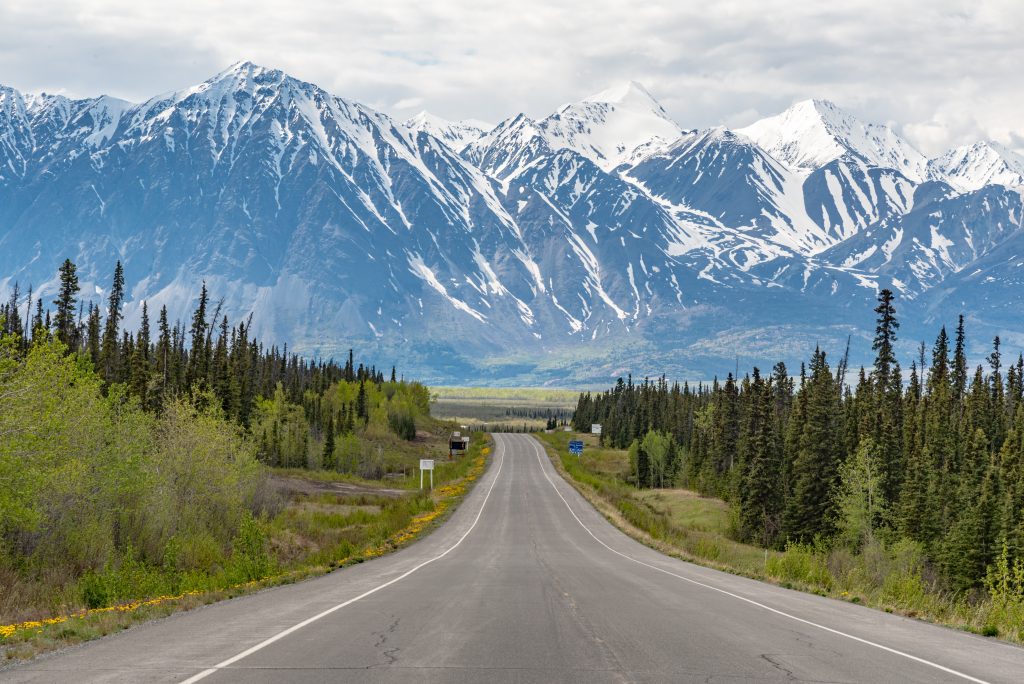 view from car on road trip of road leading to a mountain with snow peaks