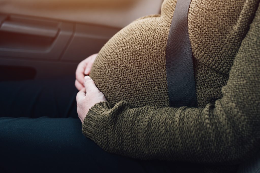view of pregnant belly buckled in car with hangs on stomach